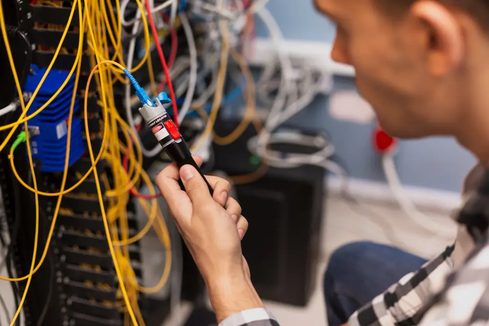 Network technician connecting cables inside a densely wired server rack
