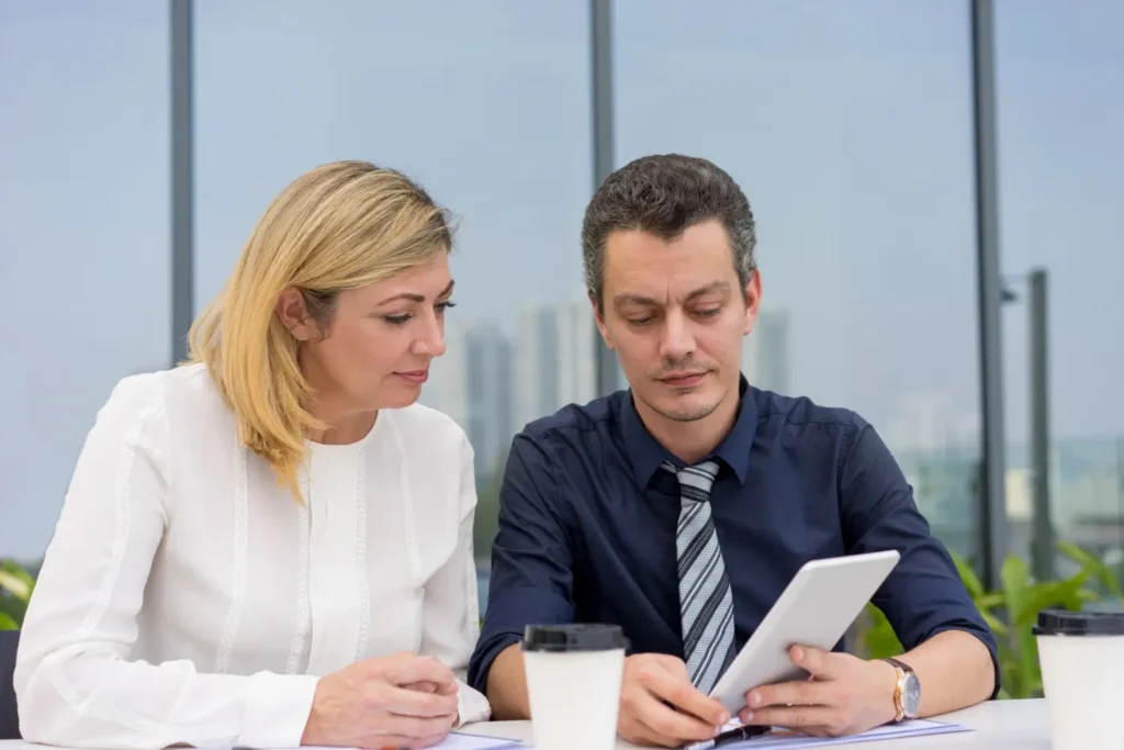 Two colleagues discussing paperwork together at a bright office table
